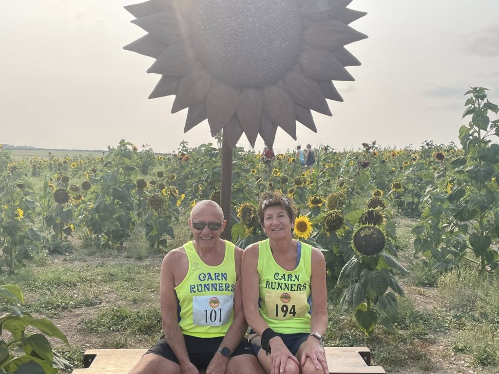 Runners in the Sunflower Stride race near Dorchester climbing Maiden Castle with views of Weymouth and Portland