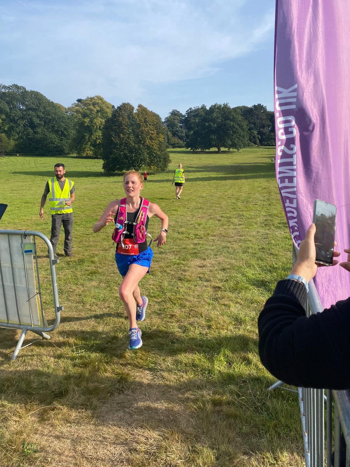 Eleanor running at Scorrier House 10K crossing the finish line as first female