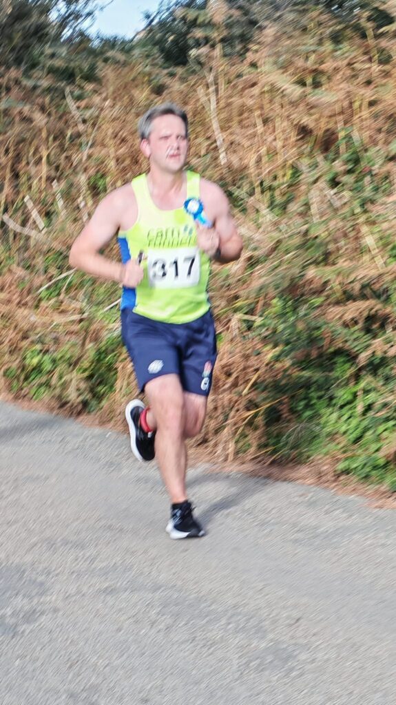 Carn Runners team at the Marazion 10K with Cornish coastline in the background