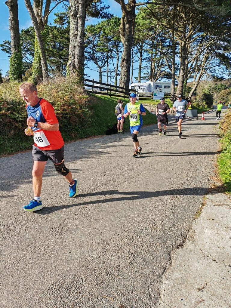 Carn Runners team at the Marazion 10K with Cornish coastline in the background