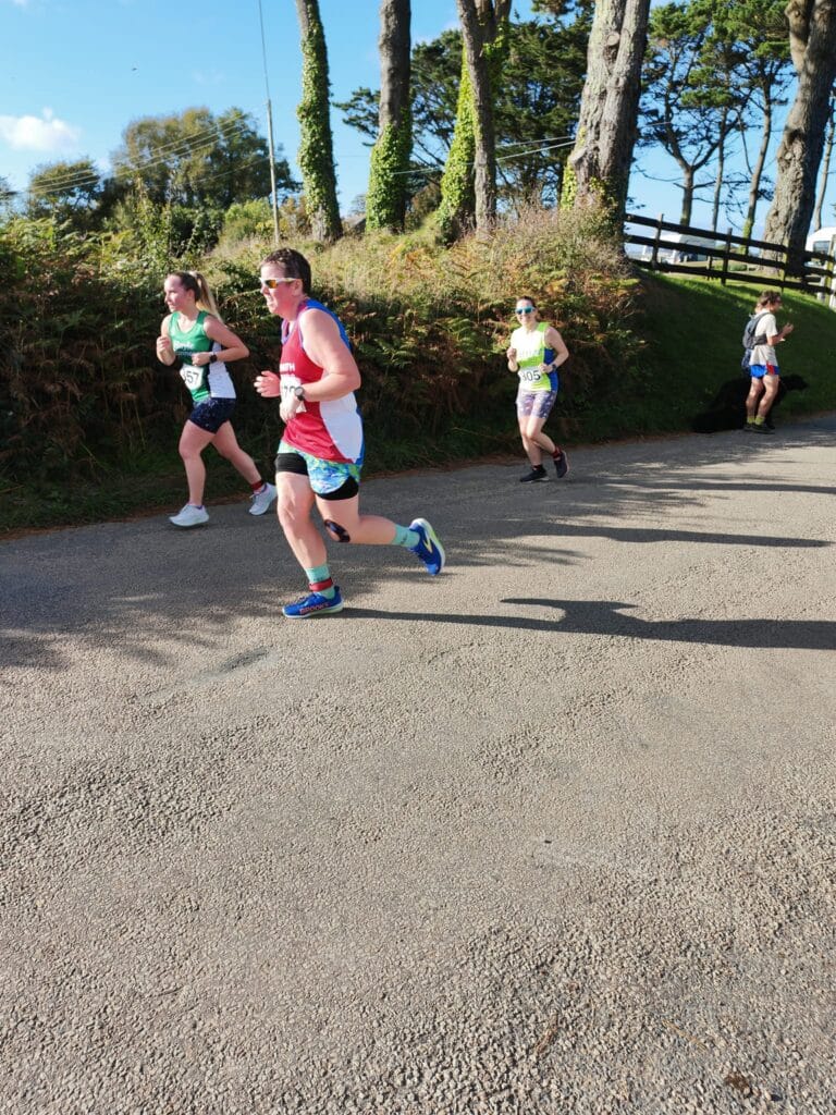 Carn Runners team at the Marazion 10K with Cornish coastline in the background