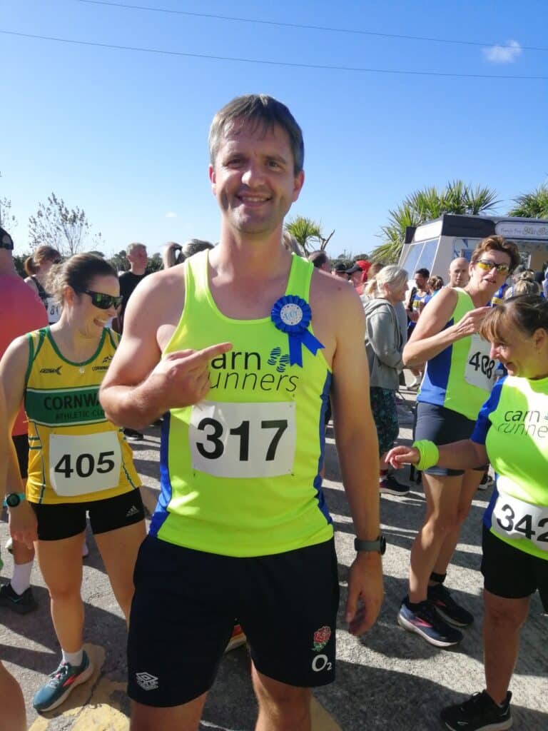 Carn Runners team at the Marazion 10K with Cornish coastline in the background